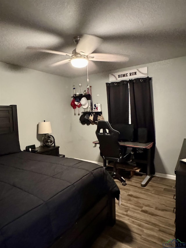 bedroom with ceiling fan, hardwood / wood-style flooring, and a textured ceiling