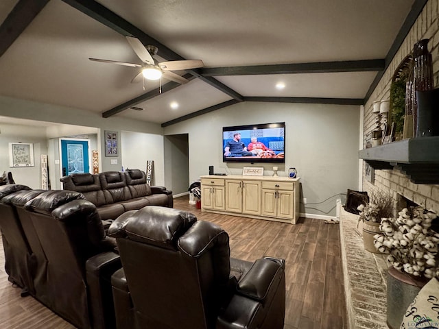 cinema with lofted ceiling with beams, ceiling fan, dark hardwood / wood-style floors, and a fireplace