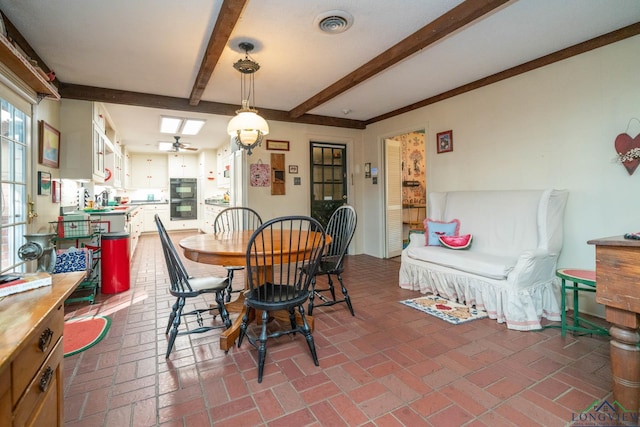 dining area featuring beamed ceiling, ceiling fan, and sink