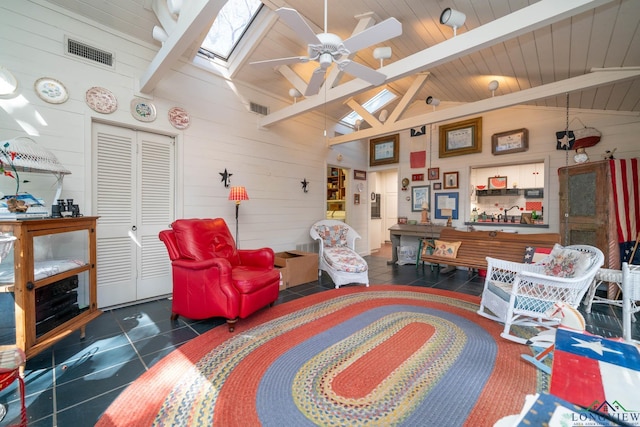 tiled living room with ceiling fan, wood walls, and a skylight