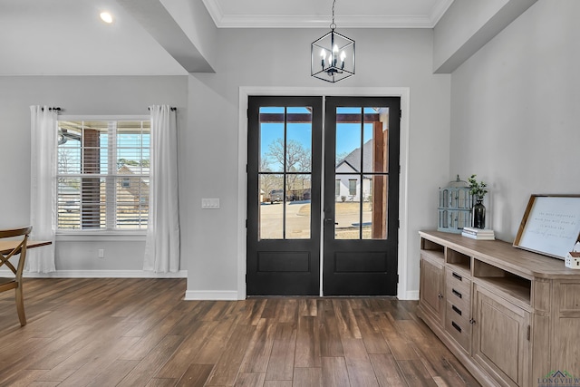 foyer with dark wood-type flooring, crown molding, french doors, and a notable chandelier