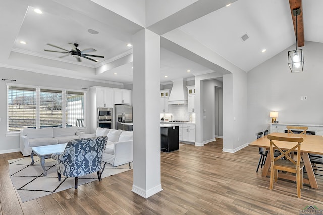 dining room with crown molding, a raised ceiling, and light hardwood / wood-style floors