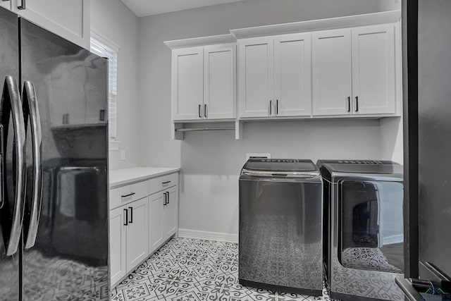 clothes washing area featuring cabinets, washer and dryer, and light tile patterned flooring