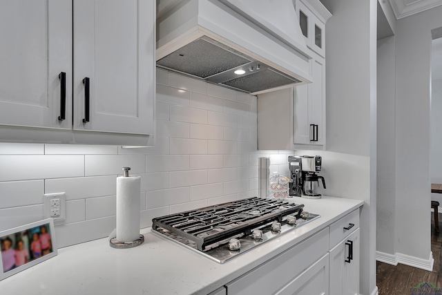 kitchen with stainless steel gas stovetop, white cabinetry, backsplash, dark wood-type flooring, and custom range hood