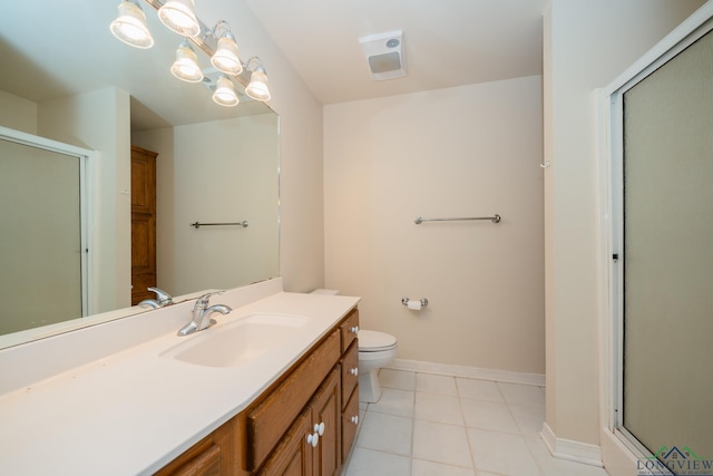 bathroom featuring tile patterned flooring, vanity, toilet, and a shower with door