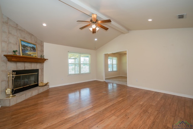 unfurnished living room featuring a tile fireplace, ceiling fan, light hardwood / wood-style floors, and lofted ceiling with beams