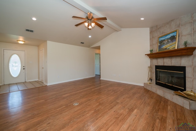 unfurnished living room with ceiling fan, lofted ceiling with beams, a fireplace, and light hardwood / wood-style flooring