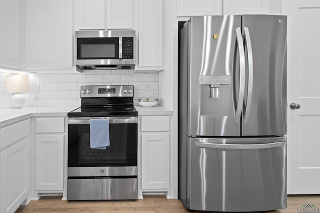 kitchen with white cabinetry, tasteful backsplash, stainless steel appliances, and light wood-type flooring