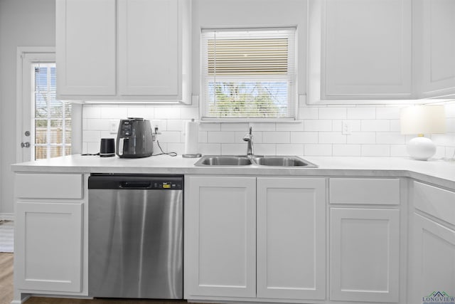 kitchen with backsplash, dishwasher, sink, and white cabinets