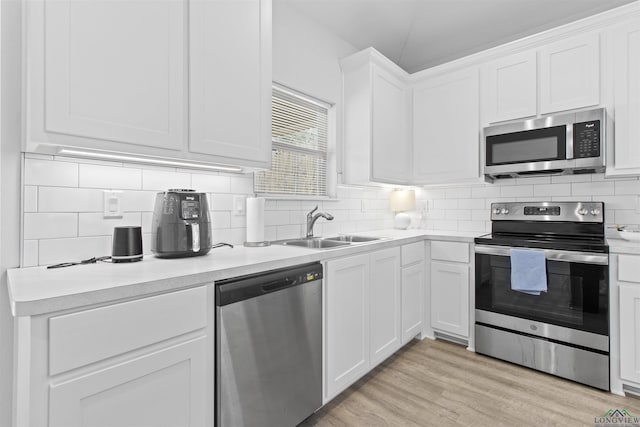 kitchen with white cabinetry, sink, light hardwood / wood-style floors, and appliances with stainless steel finishes