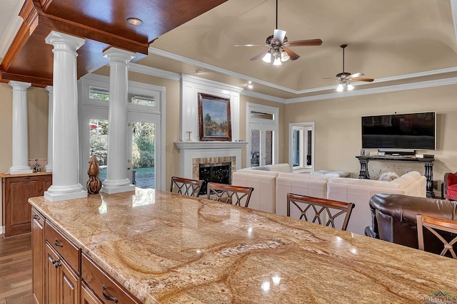 dining space with decorative columns, ceiling fan, crown molding, and a tiled fireplace