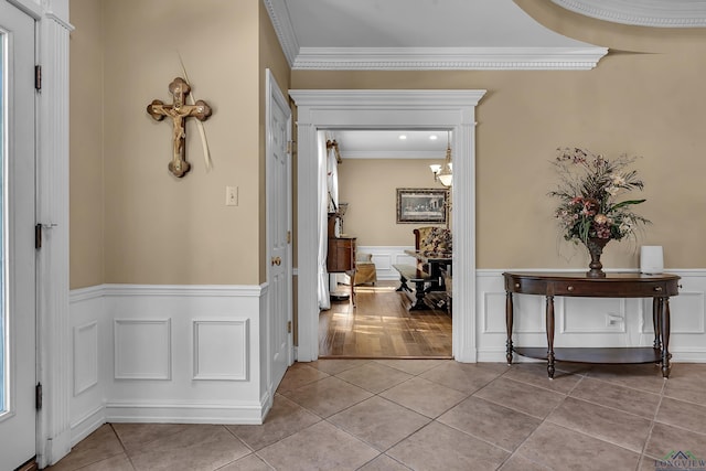 corridor featuring light tile patterned floors, an inviting chandelier, and ornamental molding