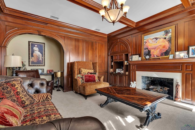 carpeted living room with wooden walls, crown molding, an inviting chandelier, beamed ceiling, and a fireplace