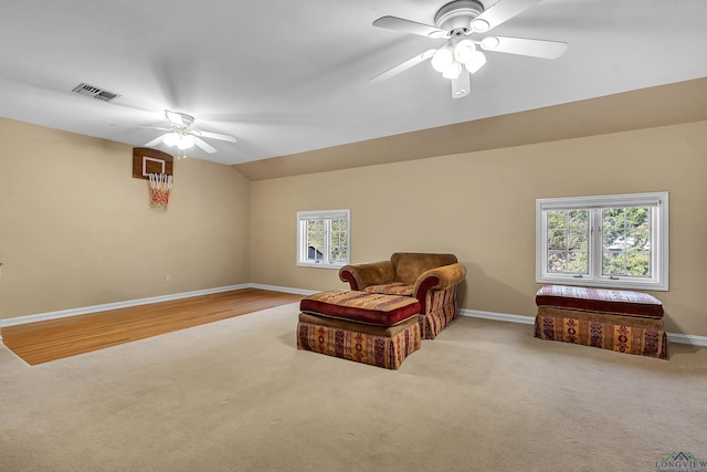 living area featuring ceiling fan, light carpet, and vaulted ceiling