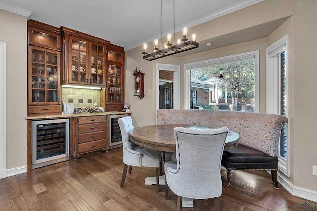 dining area with dark hardwood / wood-style floors, beverage cooler, ornamental molding, and a notable chandelier