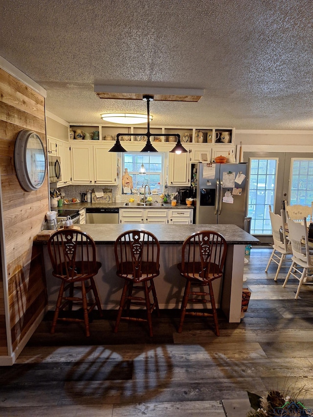 kitchen with decorative light fixtures, appliances with stainless steel finishes, a breakfast bar, and kitchen peninsula