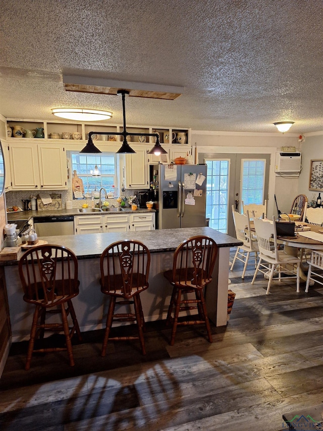 kitchen with dark hardwood / wood-style floors, decorative light fixtures, white cabinetry, a kitchen bar, and stainless steel appliances