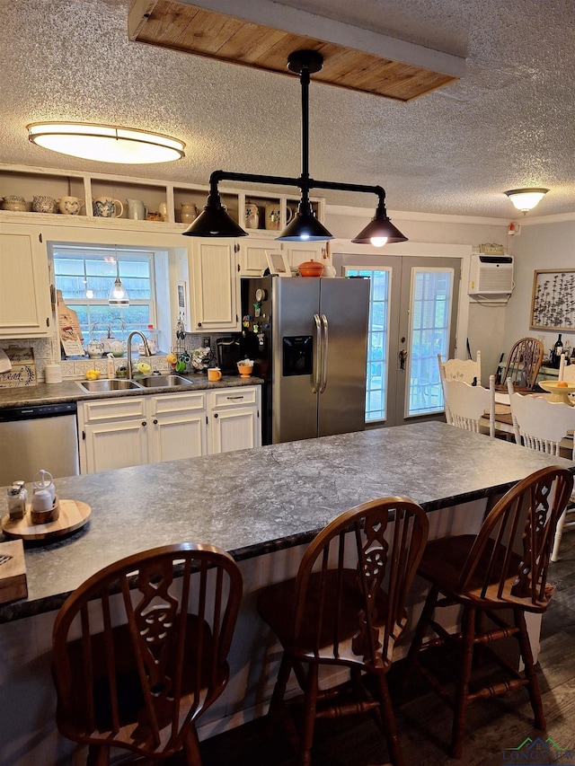 kitchen with a wealth of natural light, a wall mounted air conditioner, sink, a kitchen bar, and stainless steel appliances