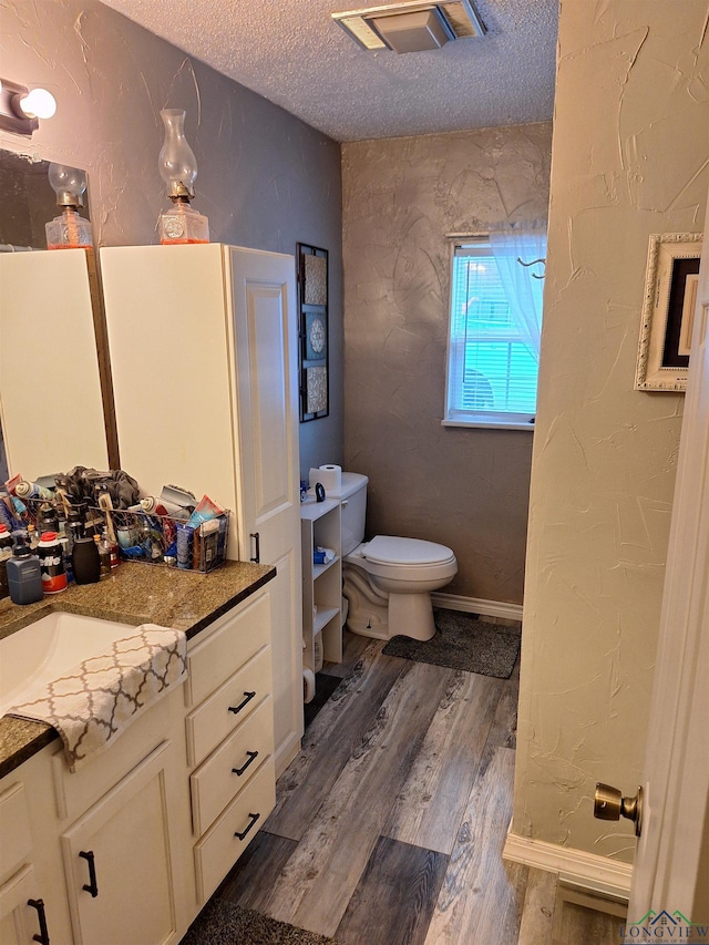 bathroom featuring vanity, wood-type flooring, a textured ceiling, and toilet