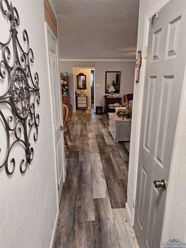 hall with wood-type flooring, crown molding, and a textured ceiling