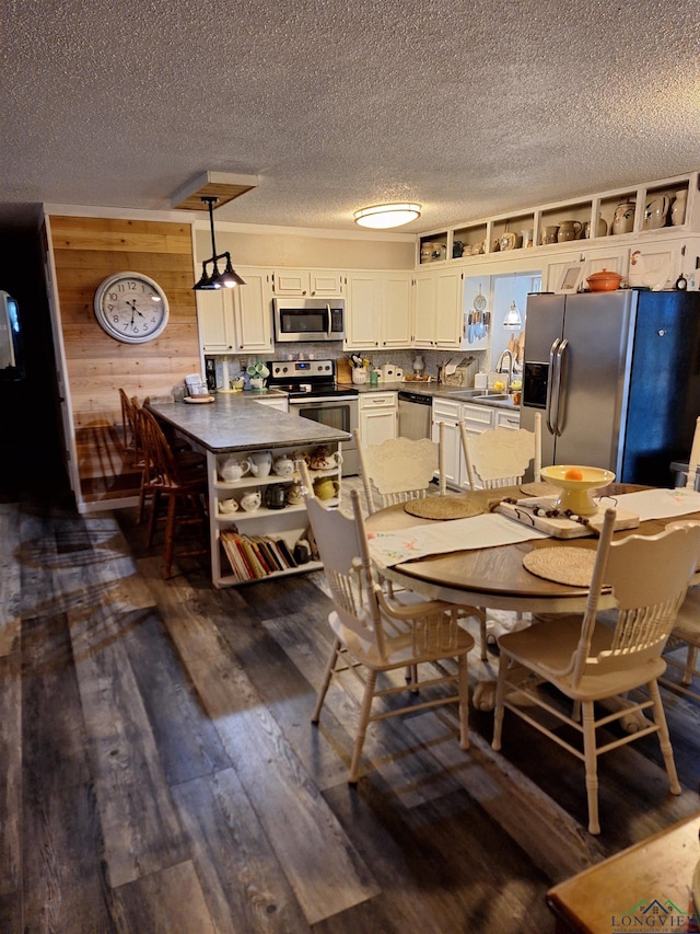 dining room with sink, wooden walls, dark hardwood / wood-style floors, and a textured ceiling