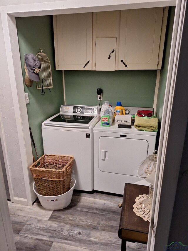 laundry area with cabinets, washing machine and dryer, and light hardwood / wood-style flooring