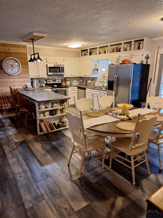 dining area featuring sink, dark hardwood / wood-style floors, a textured ceiling, and wood walls