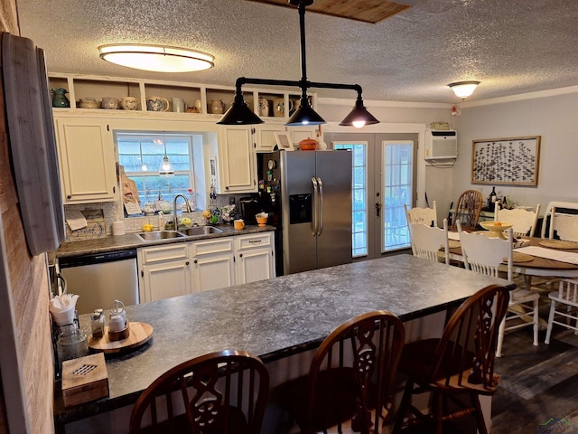 kitchen with pendant lighting, sink, appliances with stainless steel finishes, a wall mounted AC, and french doors