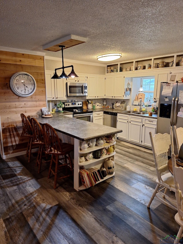 kitchen with hanging light fixtures, stainless steel appliances, a kitchen breakfast bar, white cabinets, and kitchen peninsula