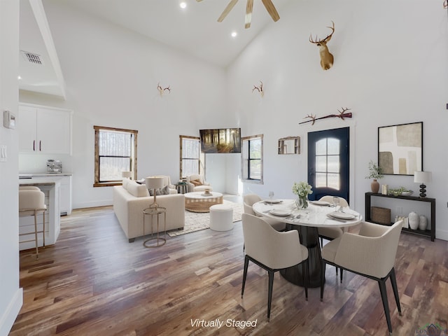 dining space featuring ceiling fan, wood-type flooring, and high vaulted ceiling