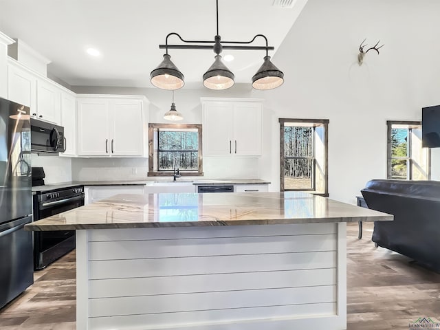 kitchen featuring light stone counters, pendant lighting, white cabinets, and a kitchen island