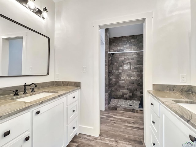 bathroom featuring hardwood / wood-style flooring, vanity, and tiled shower