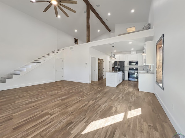 unfurnished living room featuring ceiling fan, high vaulted ceiling, dark wood-type flooring, and beam ceiling