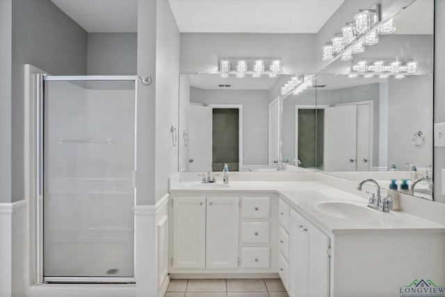 bathroom with double vanity, a stall shower, tile patterned flooring, and a sink