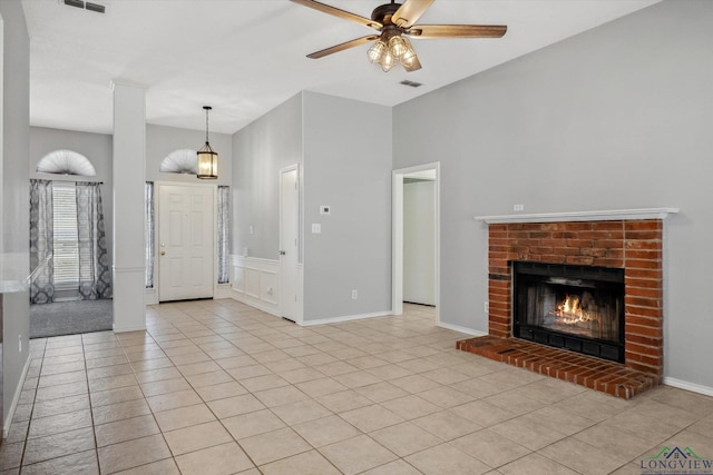 unfurnished living room with a ceiling fan, visible vents, a fireplace, and light tile patterned floors