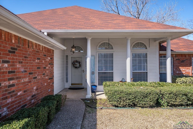 entrance to property with brick siding and roof with shingles