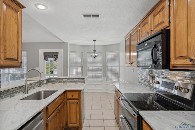 kitchen featuring stainless steel appliances, visible vents, brown cabinetry, light tile patterned flooring, and a sink