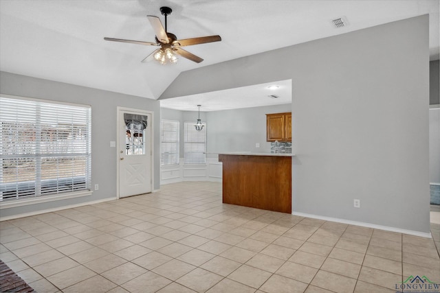 unfurnished living room with light tile patterned floors, visible vents, a ceiling fan, vaulted ceiling, and baseboards