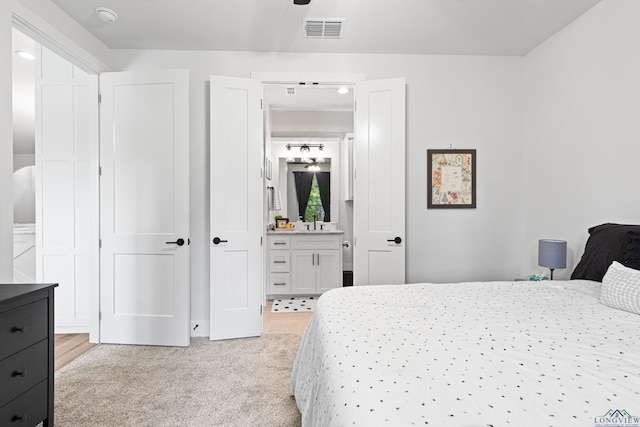 bedroom featuring light carpet and ensuite bath