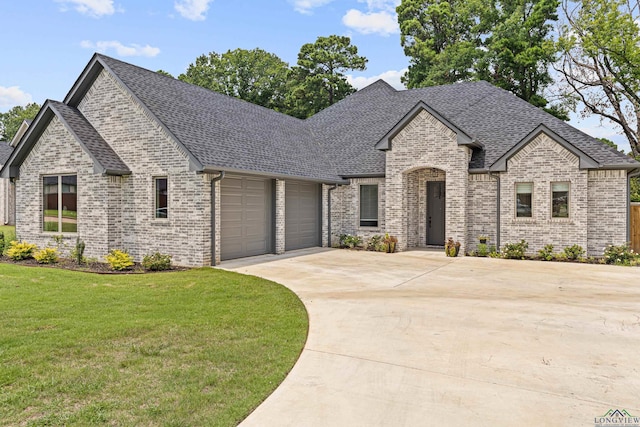 french provincial home featuring a front yard and a garage