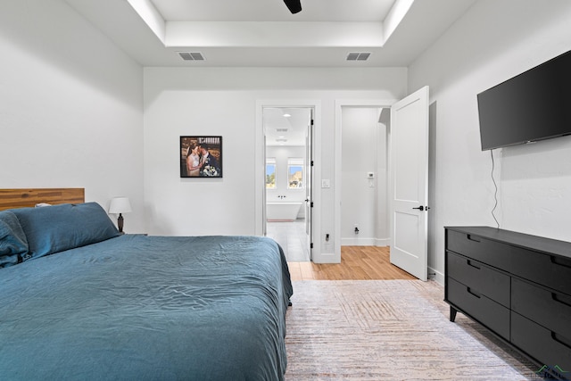 bedroom with a raised ceiling, light hardwood / wood-style flooring, and ceiling fan