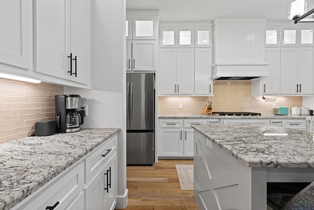 kitchen with white cabinetry, backsplash, and stainless steel fridge