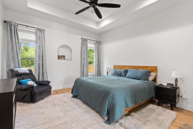 bedroom with a raised ceiling, ceiling fan, and hardwood / wood-style flooring