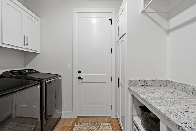 laundry area featuring cabinets, light wood-type flooring, and separate washer and dryer