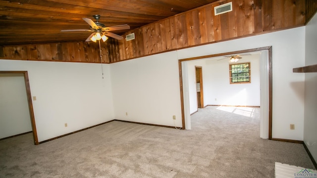 carpeted spare room featuring ceiling fan and wood ceiling