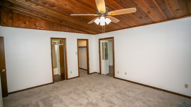 unfurnished bedroom with a walk in closet, light colored carpet, and ceiling fan