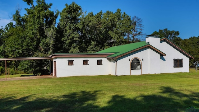 rear view of property featuring a carport and a lawn