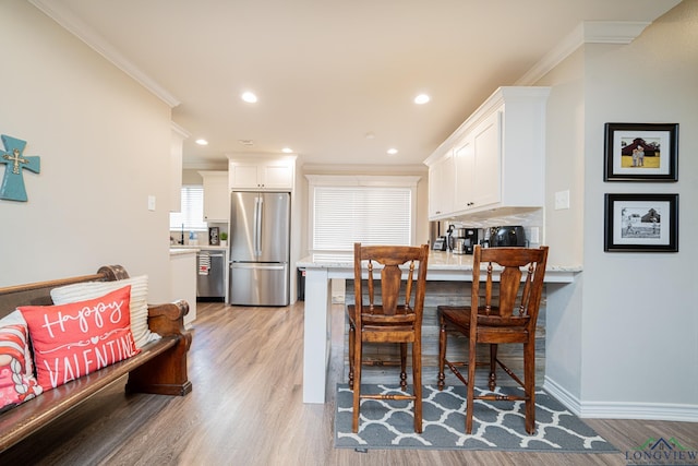 dining area featuring crown molding and light wood-type flooring