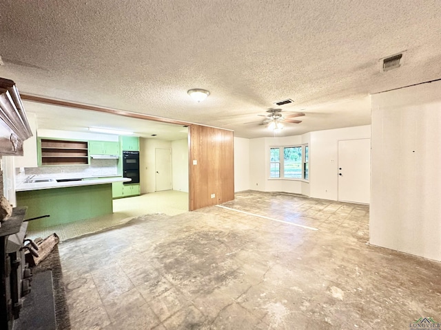 unfurnished living room with a textured ceiling, a ceiling fan, and visible vents