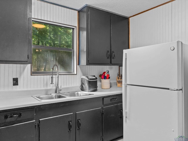 kitchen with sink, white refrigerator, a textured ceiling, and ornamental molding